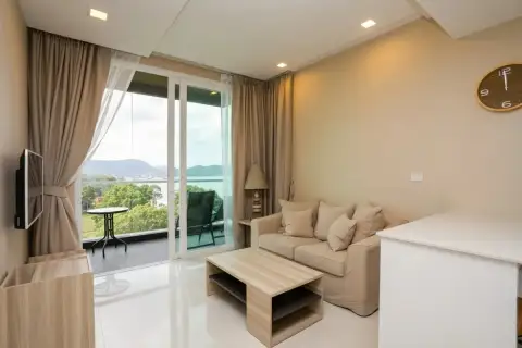 1 Bedroom Condo for Sale at Del Mare cozy living room with neutral sofa, wooden coffee table, and glass doors opening to sea-view balcony