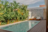 4 Bedroom House for Sale at Dhewee Resort private swimming pool surrounded by tropical plants and a stone wall.