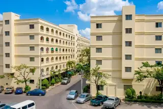 Nirun Grand Ville exterior view of two light yellow buildings with street parking and cars.