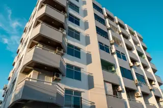 Sweet Condo 2 exterior, a modern high-rise building with multiple balconies and air conditioning units under a blue sky.