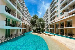 Paradise Park large resort-style swimming pool with bridges, palm trees, and sun loungers, surrounded by condo buildings.
