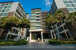 Siam Oriental Tropical Garden: Narrow swimming pool between modern condo buildings with lounge chairs and a small palm tree.