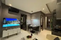 1 Bedroom Condo for Sale at Zenith Pattaya living room with wall-mounted TV, dining table, and pendant lighting