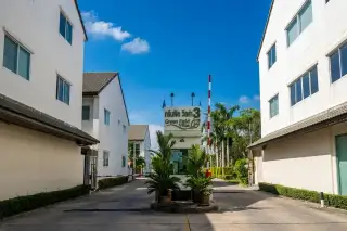 Green Field Villas 3 main entrance with guardhouse, property sign, boom barrier, and residential buildings under a blue sky.