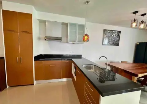 2 Bedroom Condo for Rent at Gardenia Pattaya wooden kitchen with black countertop, stove hood, and pendant light