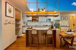 Gardenia Pattaya kitchen and dining area with a breakfast bar, wine rack, light cabinetry, and a wooden dining table.