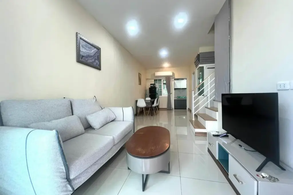 3 Bedroom House for Rent at Golden Town Pattaya living room with gray sofa, TV console and staircase view