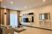 3 Bedroom House for Rent at Garden Ville 1 bright living room with wall-mounted TV unit, leather sofa, and large curtained windows