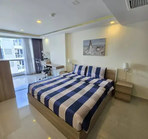 1 Bedroom Condo for Rent at Grand Avenue Residence master bedroom with striped bedding, desk, and city view window