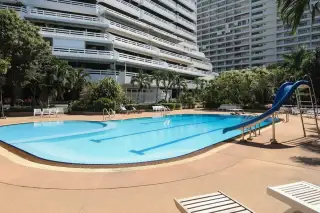 Grand Condotel outdoor swimming pool surrounded by tall palm trees and tropical greenery.