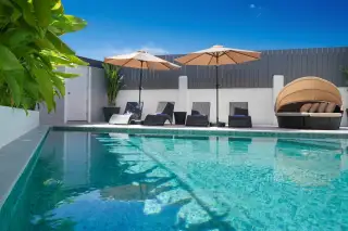 Grand Tanyawan Home large community swimming pool with houses and blue sky in the background.