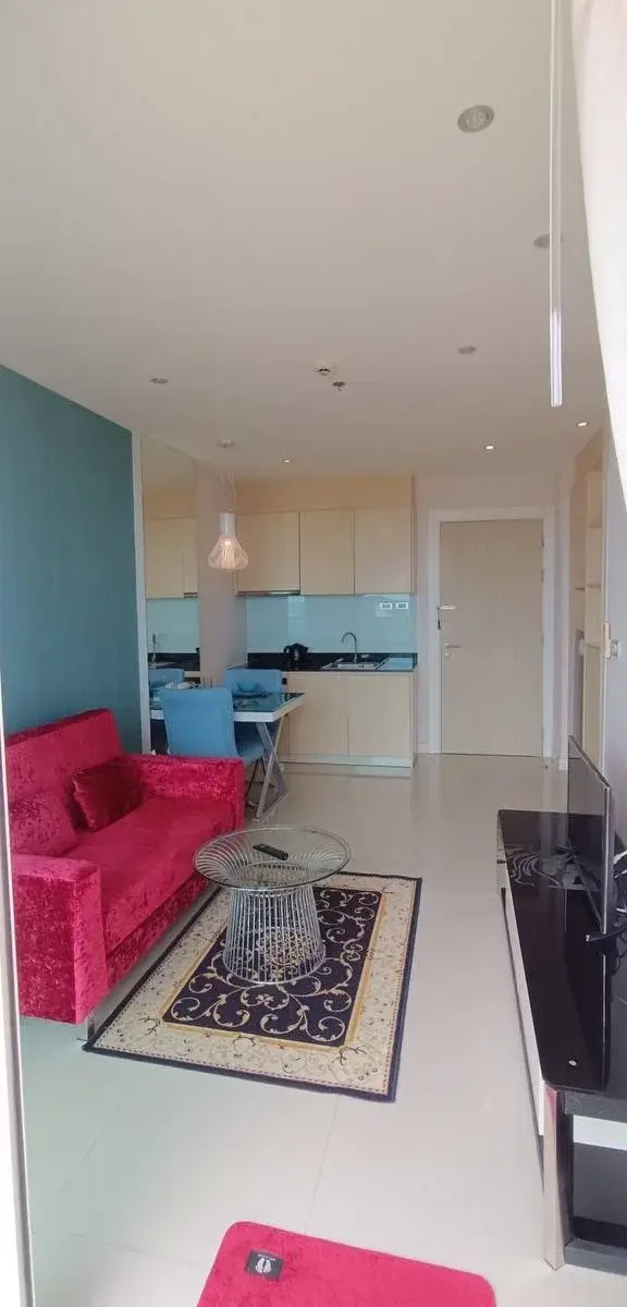 1 Bedroom Condo for Rent at Grande Caribbean living room with pink sofa, patterned rug, and open kitchen view