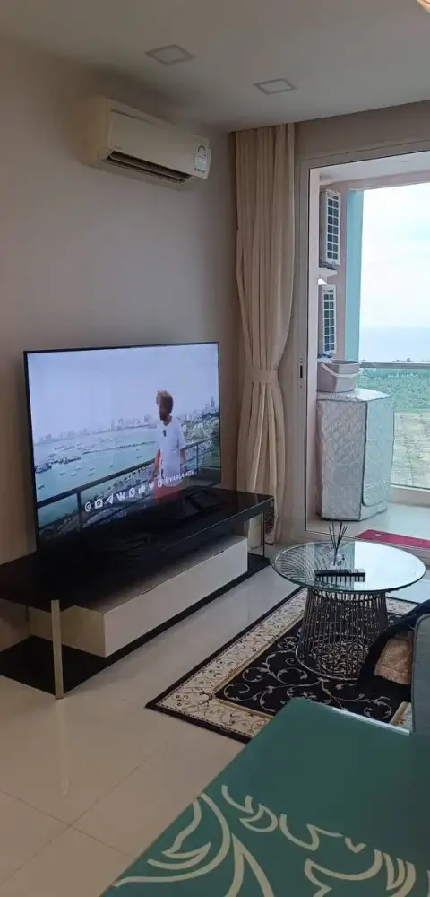 1 Bedroom Condo for Rent at Grande Caribbean living area with flat-screen TV, glass coffee table, and balcony sea view