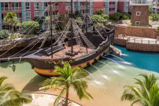 Grande Caribbean pirate ship water park feature with water jets, pool, and surrounding residential buildings.