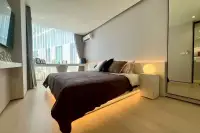 1 Bedroom Condo for Sale at Celine Wongamat: Bedroom with a large bed, built-in lighting, and bright window with curtains.