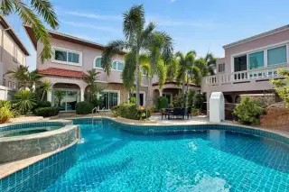 Baan Nai Fuun Village, large house with lush tropical garden, green lawn, and curved pathway.