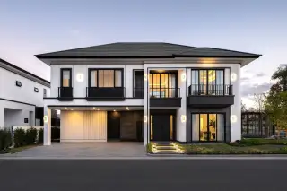 Chieftain contemporary two-story house with white exterior, black accents, a covered entrance, and a paved driveway.