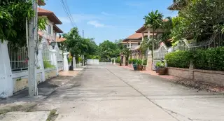 Eakmongkol Village Chaiyapruek 2 lush green garden area with potted plants, grass, and a brick wall.