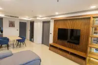 3 Bedroom Condo for Rent at Cosy Beach View open-plan living and dining room with blue velvet chairs and wooden entertainment wall