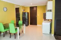 1 Bedroom Condo for Sale at Wongamat Privacy open-plan dining area with green chairs, black fridge, kitchen, and washing machine