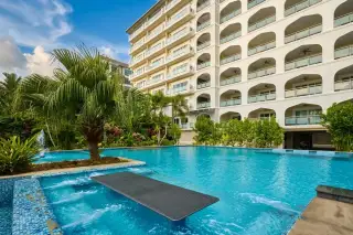 Tudor Court outdoor swimming pool with a diving board, palm tree, and the condo building in the background.