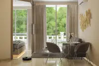 1 Bedroom Condo for Sale at Harmonia City Garden living area with dining table, gray sofa chairs and balcony overlooking tropical garden