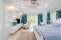 4 Bedroom House for Sale in East Pattaya master bedroom with blue bedding, teal curtains, and balcony access