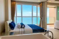 1 Bedroom Condo for Sale at Cetus Beachfront bedroom with double bed, blue bedding, bathtub, and floor-to-ceiling ocean view window
