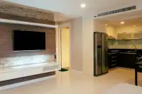 3 Bedroom Condo for Sale at Apus living room with wood-panel TV wall and open kitchen with dark cabinetry and side-by-side fridge
