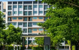 G Condo Sriracha building entrance signage with multi-story facade and tree-lined driveway