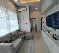 3 Bedroom House for Rent in Huai Yai cozy living room with gray sectional sofa and wall-mounted TV