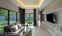 3 Bedroom House for Rent in Huai Yai living room with leather sofa, wall-mounted TV, and pool view windows