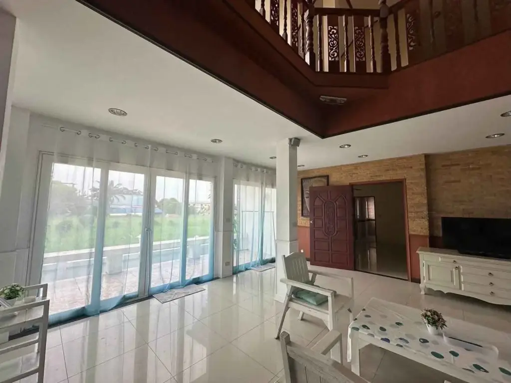 5 Bedroom House for Rent in Huai Yai living room with double-height ceiling, wooden mezzanine railing and garden view