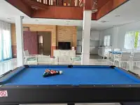 5 Bedroom House for Rent in Huai Yai pool table room with stone accent wall, TV console and adjoining kitchen