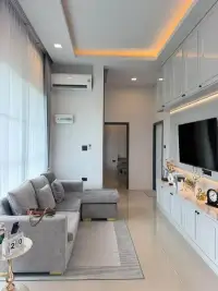 3 Bedroom Townhouse for Rent in Huai Yai gray sectional sofa facing wall-mounted TV and white cabinetry