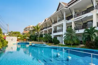 Sunrise Beach Residence outdoor swimming pool with blue mosaic tiles, bordered by a multi-story building and palm trees.