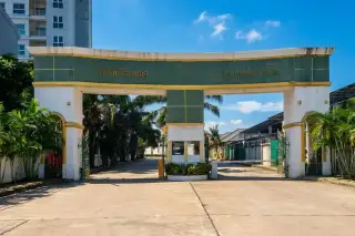 The Imperial Place entrance gate with a guardhouse, property sign, and palm trees, leading into the complex.