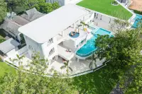 6 Bedroom House for Sale in Huai Yai bird's eye drone view of white villa with curved infinity pool and green landscaping