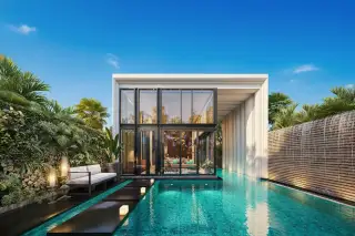 Inara Villa modern exterior with glass walls, pink-lit swimming pool, outdoor sofa, and lush greenery at dusk.