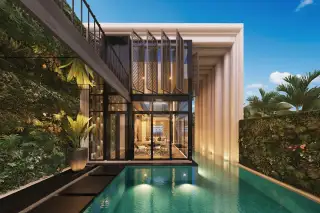 Inara Villa modern exterior with glass walls, pink-lit swimming pool, outdoor sofa, and lush greenery at dusk.