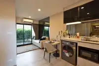 1 Bedroom Condo for Sale at The Indeed Condo Pattaya open-plan living area with kitchenette, dining table, and balcony view