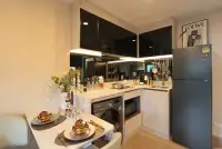 1 Bedroom Condo for Sale at The Indeed Condo Pattaya kitchen area with black cabinets, refrigerator, and dining setup