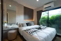 1 Bedroom Condo for Sale at The Indeed Condo Pattaya bedroom with white bedding, dark wood headboard, and garden view window