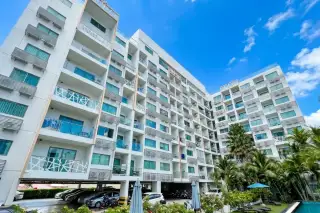 Water Park condo exterior in Pattaya showing multi-story building with balconies, palm trees, and parking area