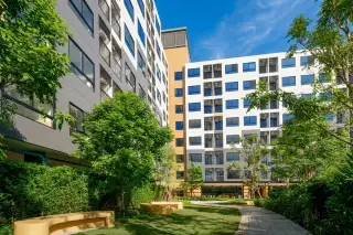 Vay Pothisan modern condominium buildings with gray facades, parking lot, and lush green landscaping.