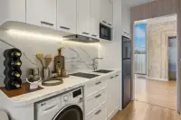 Studio Condo for Sale at Seaspire Jomtien: Compact kitchen with white cabinets, marble backsplash, and built-in washer.