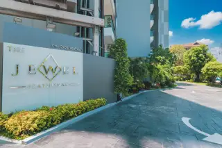 Jewel Pratumnak rooftop pool with city skyline and ocean views under a clear sky.