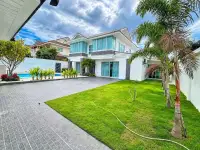 5 Bedroom House for Sale & Rent in Jomtien two-story exterior with lush lawn, palm trees, and private pool