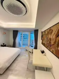 1 Bedroom Condo for Sale at Jomtien Complex bedroom with desk, wall art and city view balcony