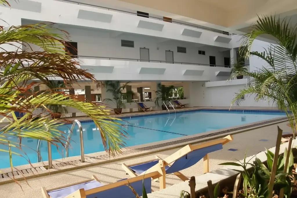 Jomtien Hill Resort Condominium outdoor swimming pool with blue water, lounge chairs, and palm trees.